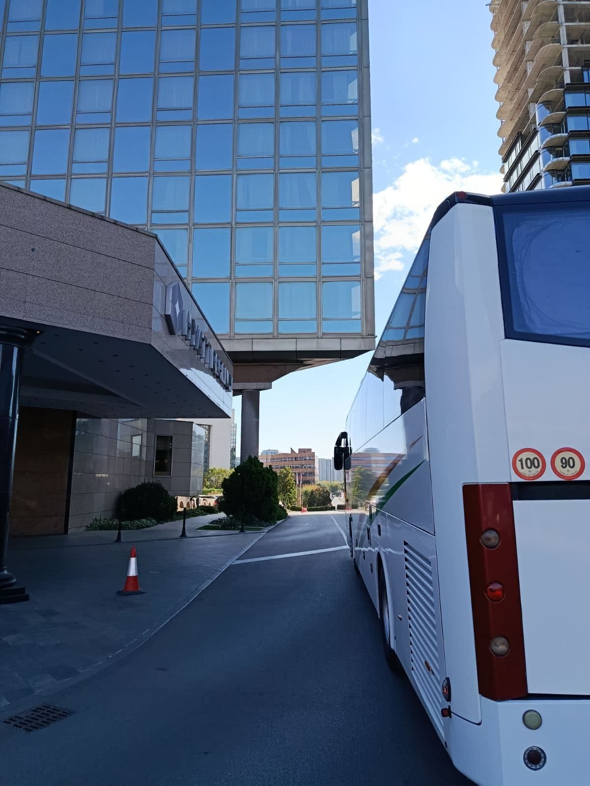 Beli autobus ispred hotela sa staklenom fasadom u Beogradu