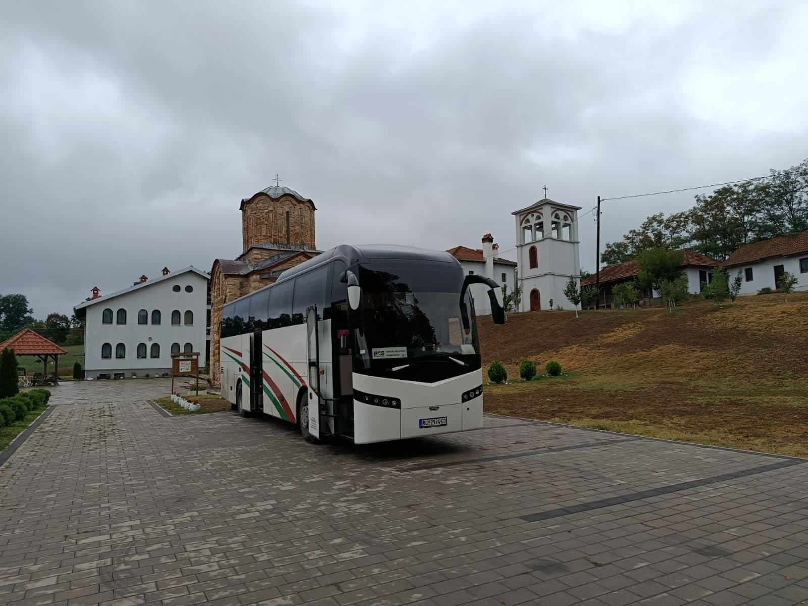 White BAS PREVOZ coach in front of a monastery church